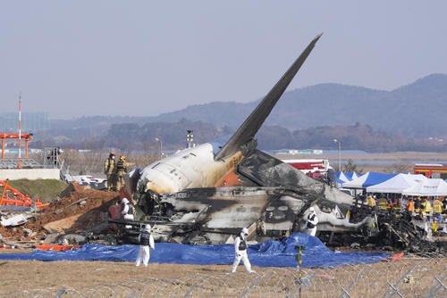Firefighters and rescue team members work near the wreckage of a passenger plane at Muan International Airport.