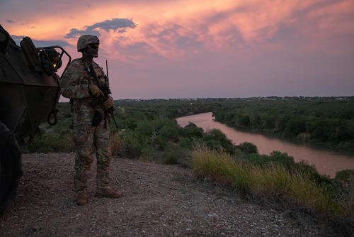 U.S. Army soldier stands beside a Stryker along the Rio Grande River