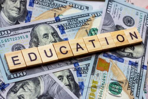 Amid U.S. $100 bills, letter tiles spell "education."