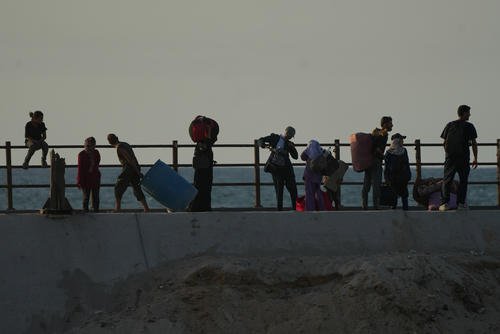 Displaced Palestinians flee northern Gaza carrying their belongings along the coastal road near Wadi Gaza