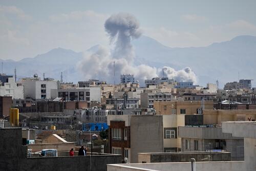 People watch from a rooftop as a plume of smoke rises after a strike in Tehran, Iran, Sunday, March 1, 2026. (AP Photo/Vahid Salemi)